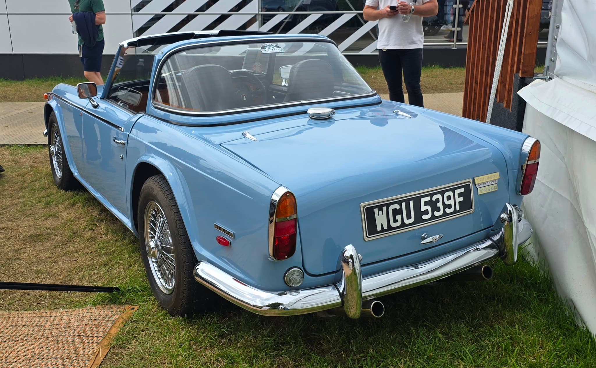 A light blue sports car seen from behind, its hardtop's rear section in place and the roof open above the seats. Opens a larger view