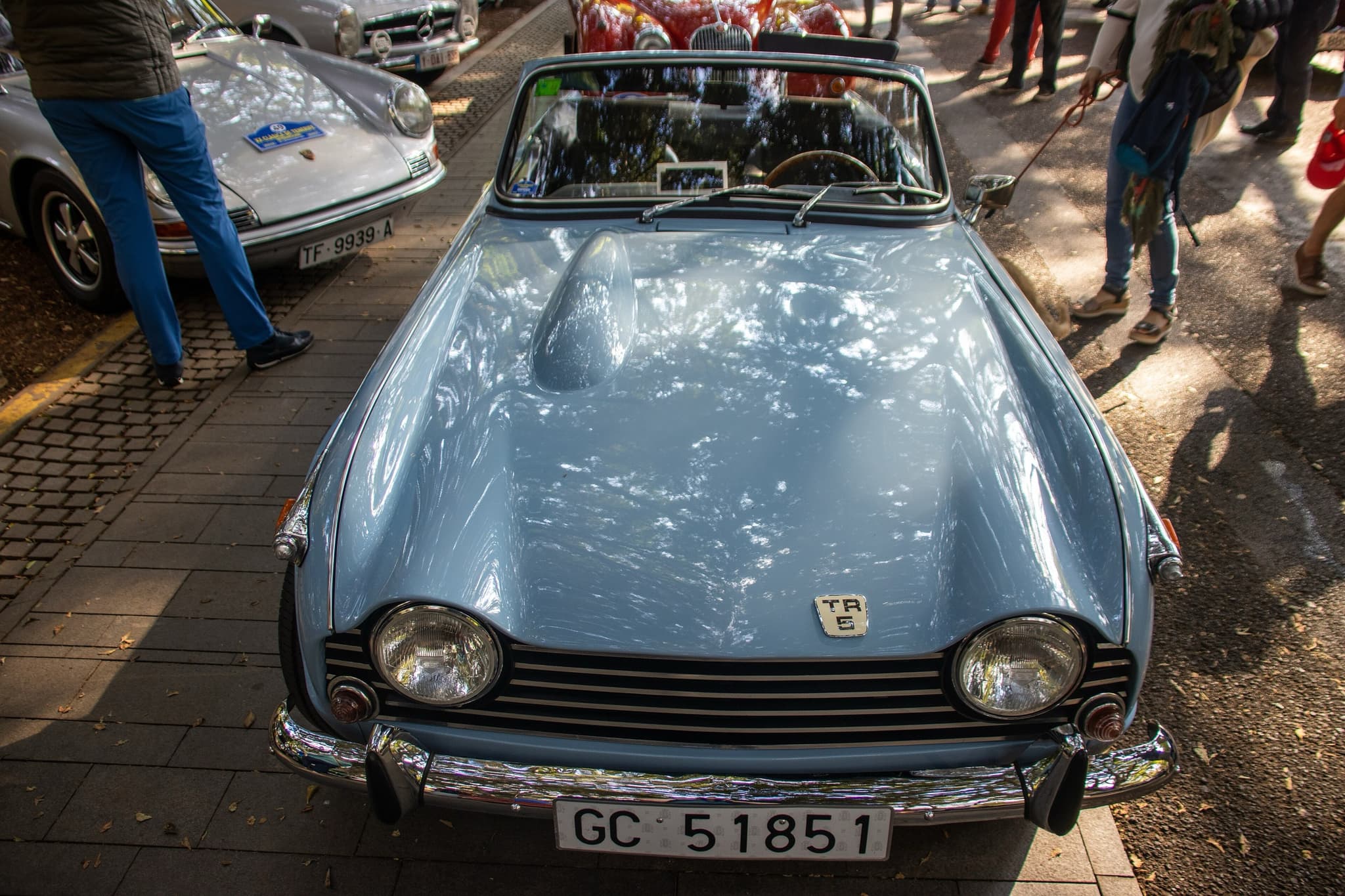A pale blue sports car seen head-on from above, showing its bonnet bulge and the small badge above the grille.